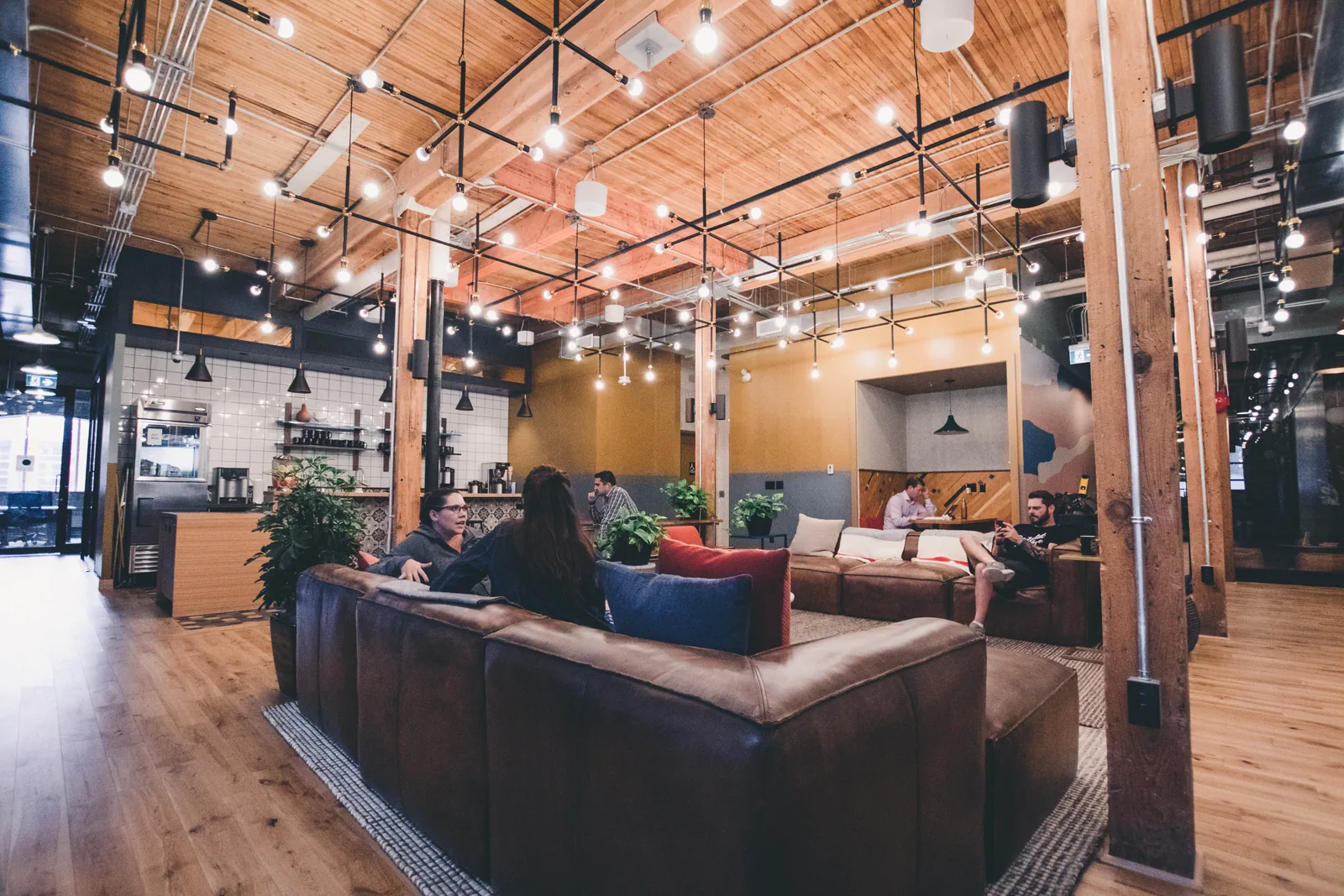 Espaço de coworking com mesas compartilhadas, computadores e pessoas trabalhando.